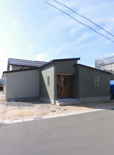 緑色のサイディングと木目の玄関ドアでカントリー風なお家